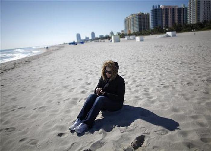A tourist wearing a jacket sit at the beach in South Beach Miami, Florida