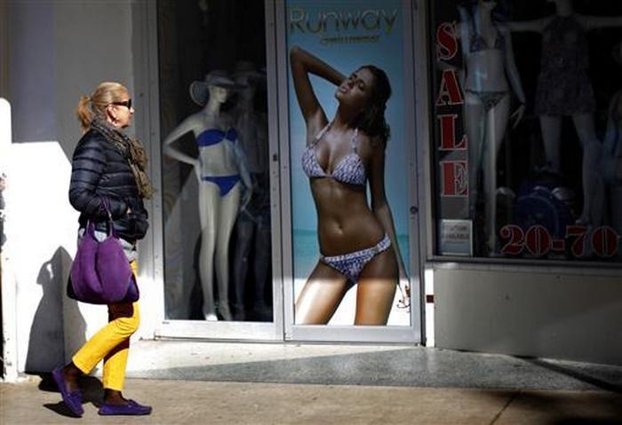 A tourist walks in front of a swimming suit store in South Beach Miami, Florida