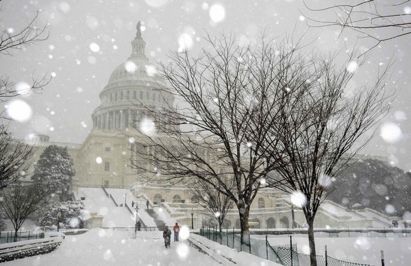People walk during snowfall at the U.S. Capitol in Washington