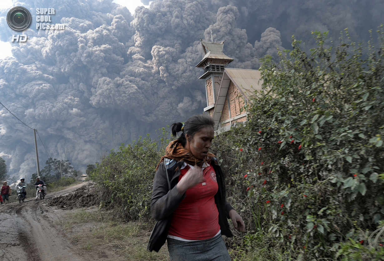 A woman flees as Mount Sinabung erupts near Bekerah village, in Karo district, North Sumatra, on February 1, 2014. Three men were burned and taken to hospital after being engulfed in heat clouds of Mount Sinabung in Indonesia, local officials said. (Photo by Sutanta Aditya/AFP Photo)